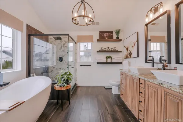 a spacious bathroom with a granite countertop sink a toilet a mirror and a large window