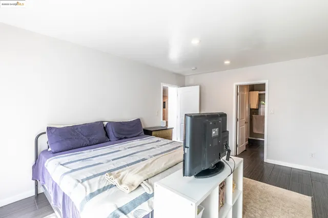 a bedroom with a bed tv and wooden floor
