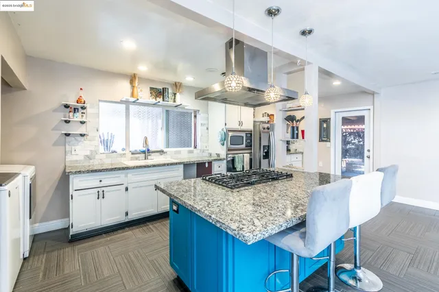 a kitchen with stainless steel appliances granite countertop a stove a refrigerator a kitchen island a sink and a refrigerator