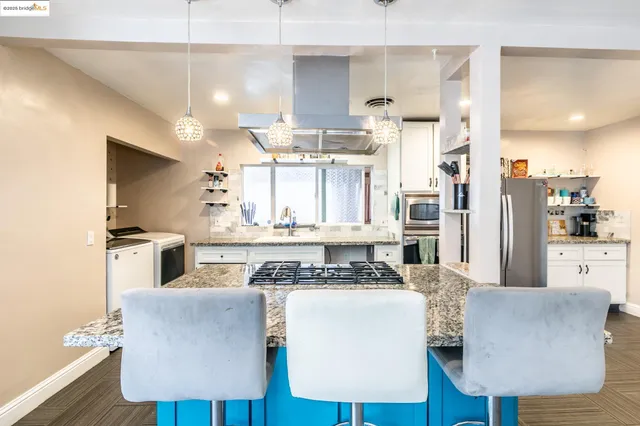 a kitchen with stainless steel appliances kitchen island granite countertop a refrigerator and a stove