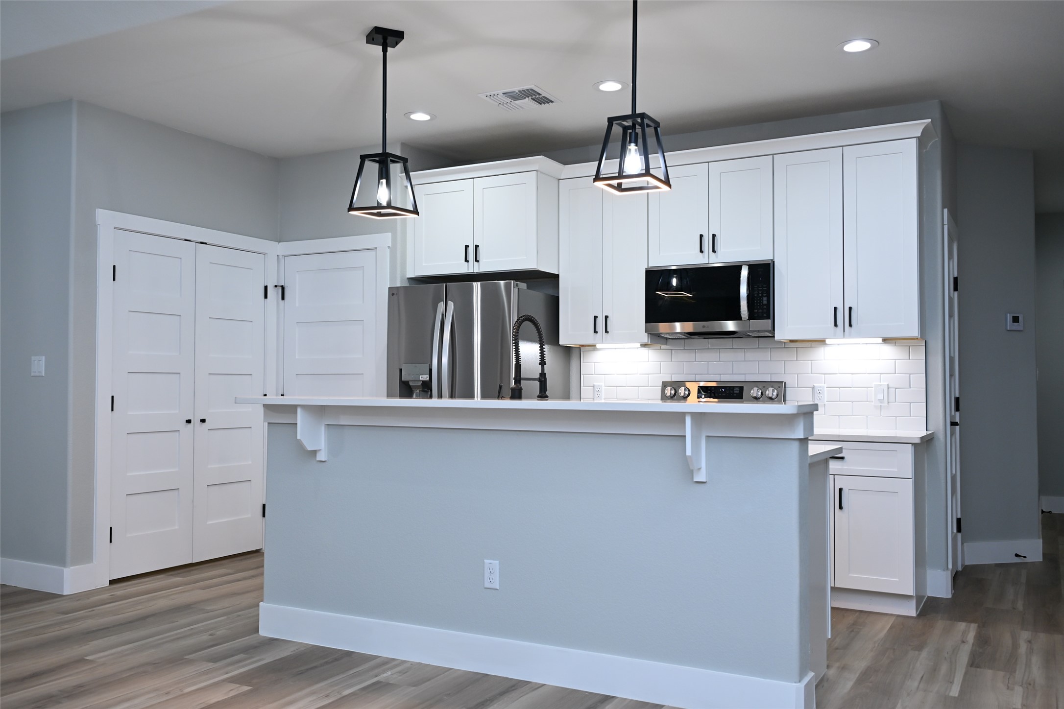 516 North Hackberry Avenue Luling, TX 78648 - Photo 16 of 36 Kitchen with white cabinets, stainless steel appliances, backsplash, dark wood-type flooring, and a kitchen bar