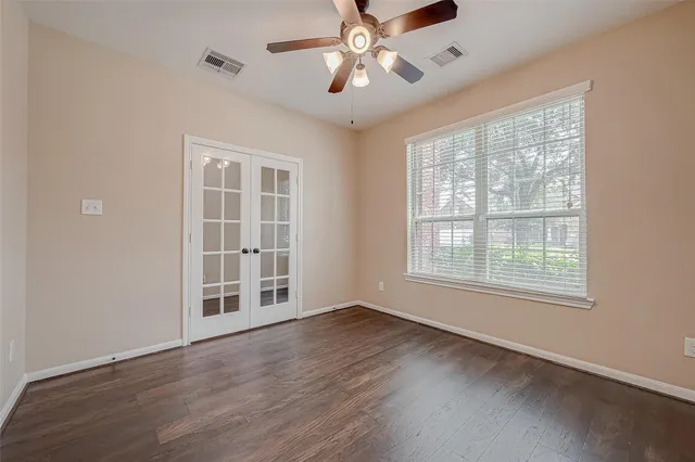 a view of an empty room with wooden floor and windows