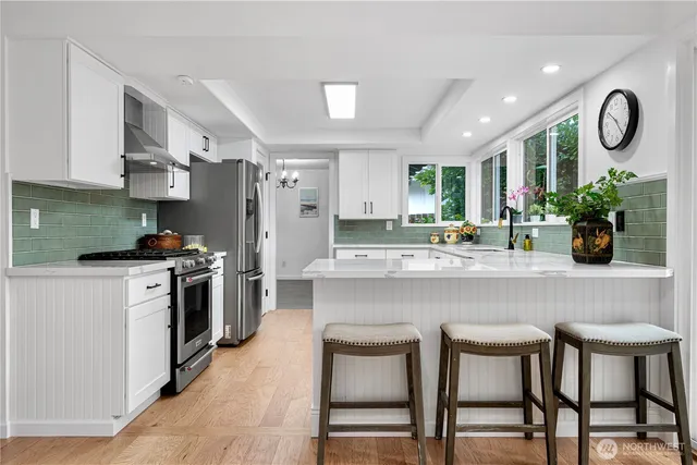 a kitchen with stainless steel appliances granite countertop a table chairs stove top oven and sink