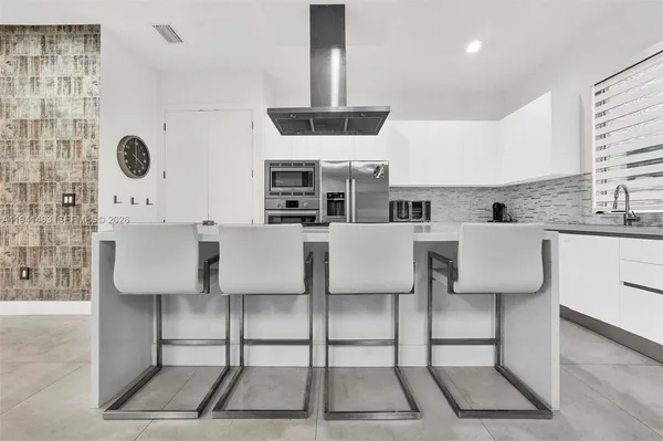 a kitchen with stainless steel appliances a stove a sink and white cabinets