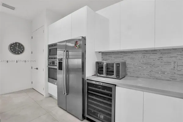 a kitchen with stainless steel appliances granite countertop a refrigerator a sink dishwasher a stove and white cabinets