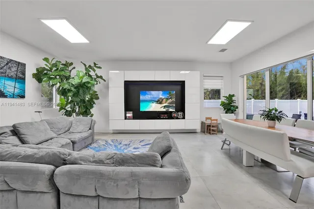 a living room with furniture kitchen view and a potted plant