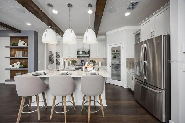 a kitchen with stainless steel appliances a dining table chairs and a refrigerator