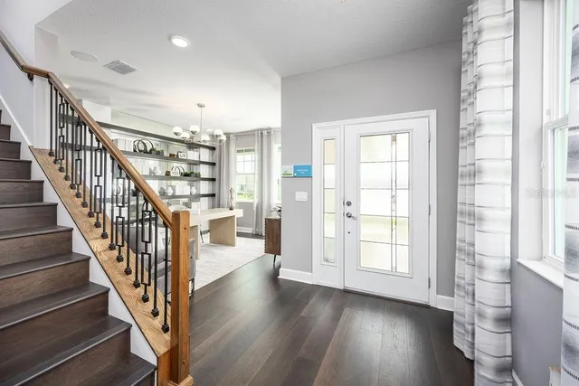 an entryway space with wooden floor and windows