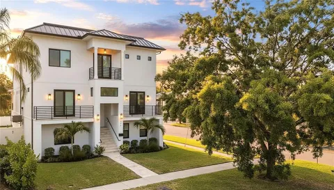 a view of a white house with large windows and a tree