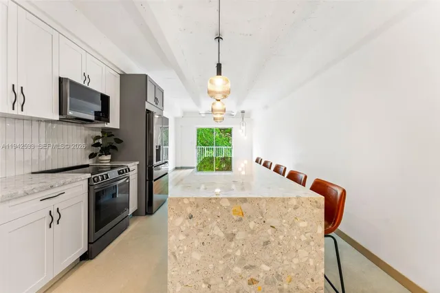 a kitchen with white cabinets a sink a window and stainless steel appliances