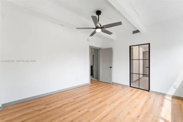 a view of empty room with wooden floor and fan