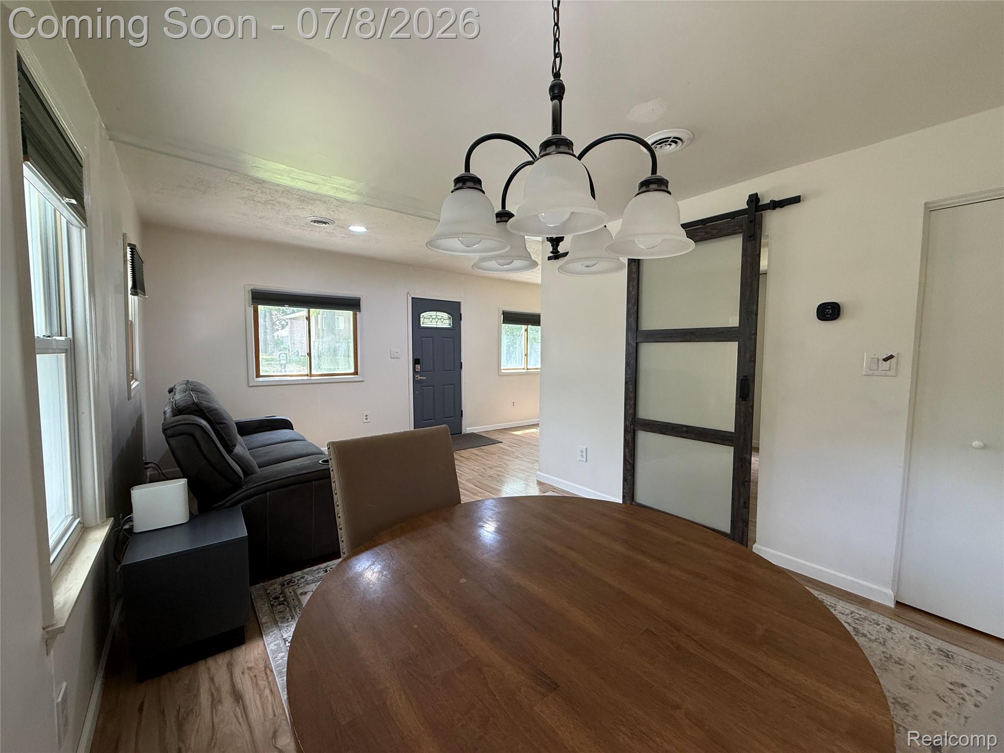 756 Cedarlawn Road Waterford, MI 48328 - Photo 6 of 34 Open-concept dining area featuring a dark wood-finish barn door, overhead chandelier, and wood-finish flooring