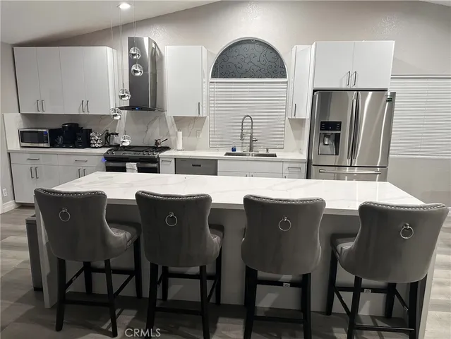 a kitchen with stainless steel appliances granite countertop a dining table chairs refrigerator and sink