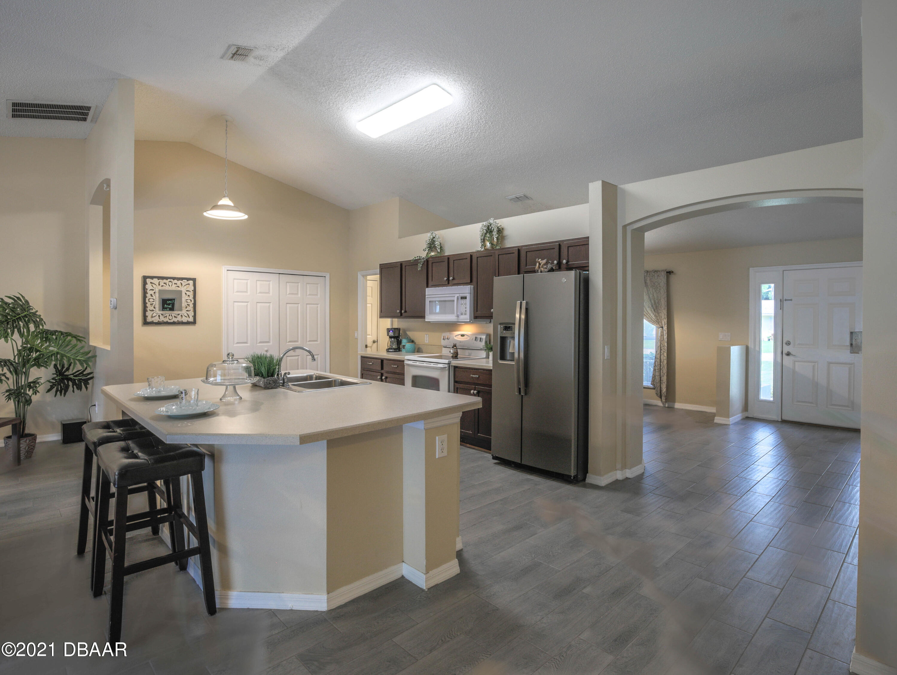 1811 Lime Tree Drive Edgewater, FL 32132 - Photo 5 of 35 a kitchen with stainless steel appliances kitchen island a table chairs in it and wooden floors