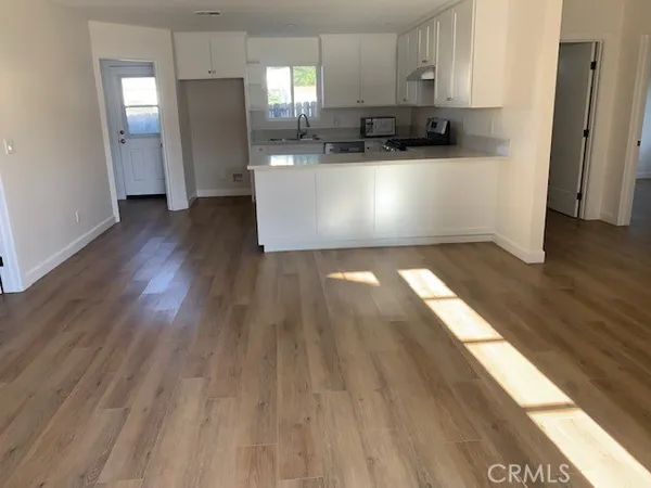 a view of kitchen with stainless steel appliances wooden floor and window