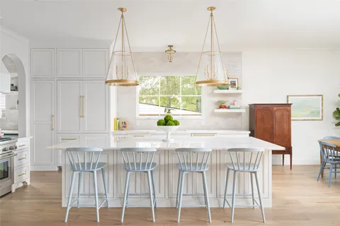 a kitchen with a table chairs and white wooden cabinets