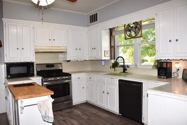 a kitchen with stainless steel appliances granite countertop a stove a sink and a microwave