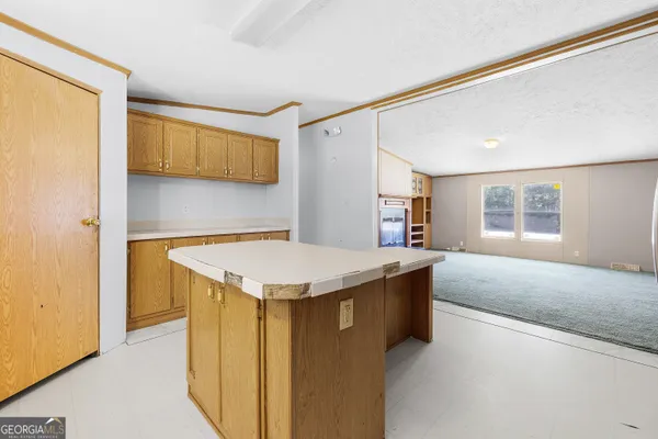 a living room with stainless steel appliances kitchen island a sink and a refrigerator