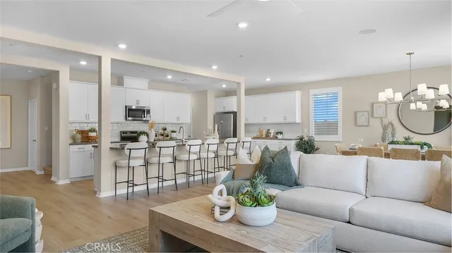 a living room with furniture kitchen view and a chandelier