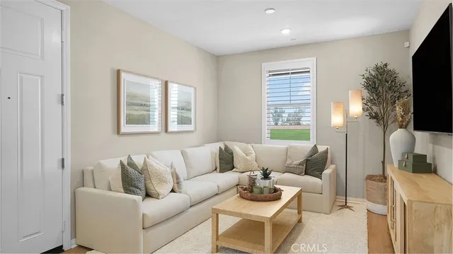 a living room with furniture a flat screen tv and a window