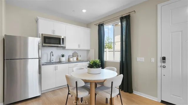 a kitchen with stainless steel appliances a dining table a microwave a refrigerator and a view of dining room