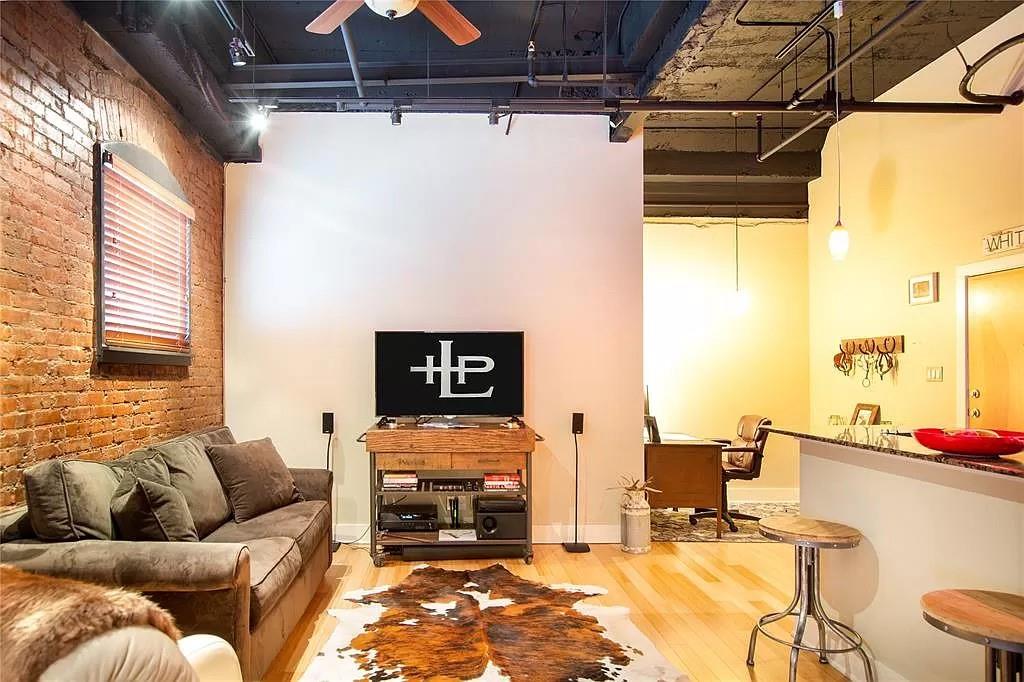 910 Houston Street, Unit 604 Fort Worth, TX 76102 - Photo 9 of 14 Living area with brick wall, light wood-type flooring, and a ceiling fan