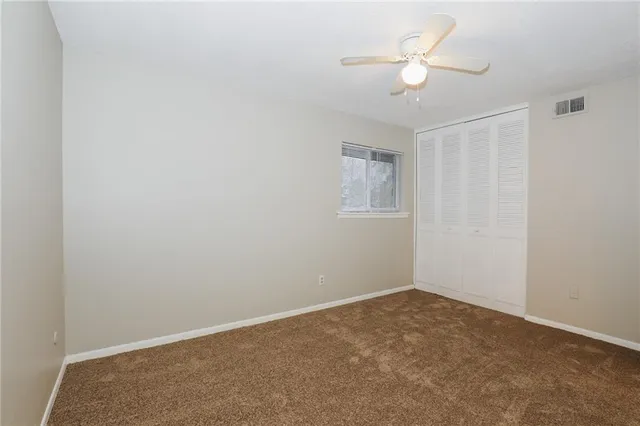 an empty room with a chandelier fan and windows