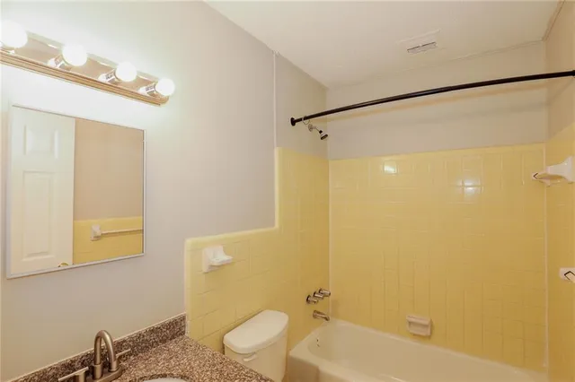 a bathroom with a granite countertop sink mirror and a bathtub