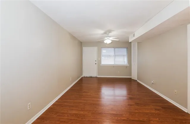 a view of an empty room with wooden floor and window