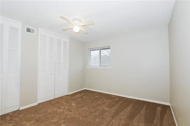 an empty room with windows and fan