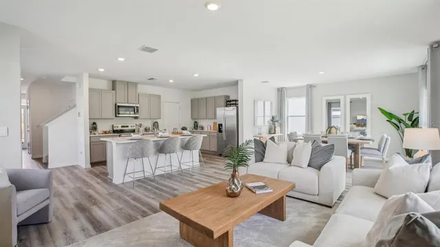 a living room with white couches and a dining table with kitchen view