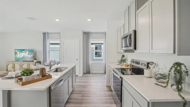 a kitchen with stainless steel appliances a sink dishwasher stove refrigerator and microwave with wooden floor