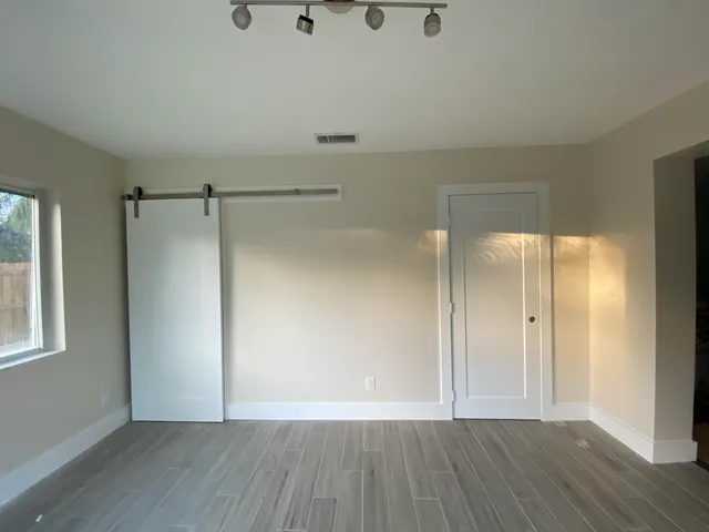 a view of an empty room with wooden floor and a window
