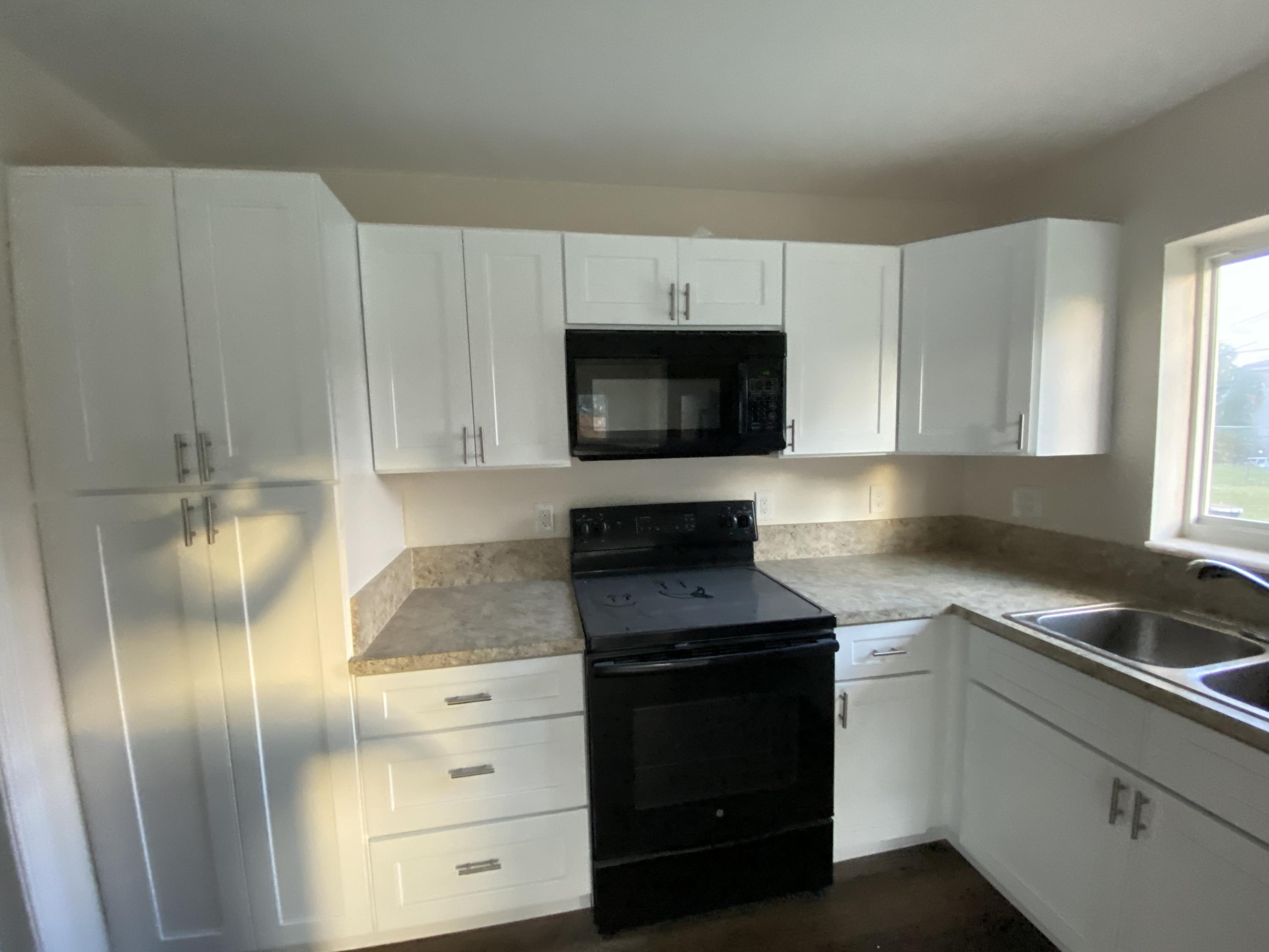 124 Northwest 9th Street Boca Raton, FL 33432 - Photo 9 of 18 a kitchen with white cabinets and stainless steel appliances