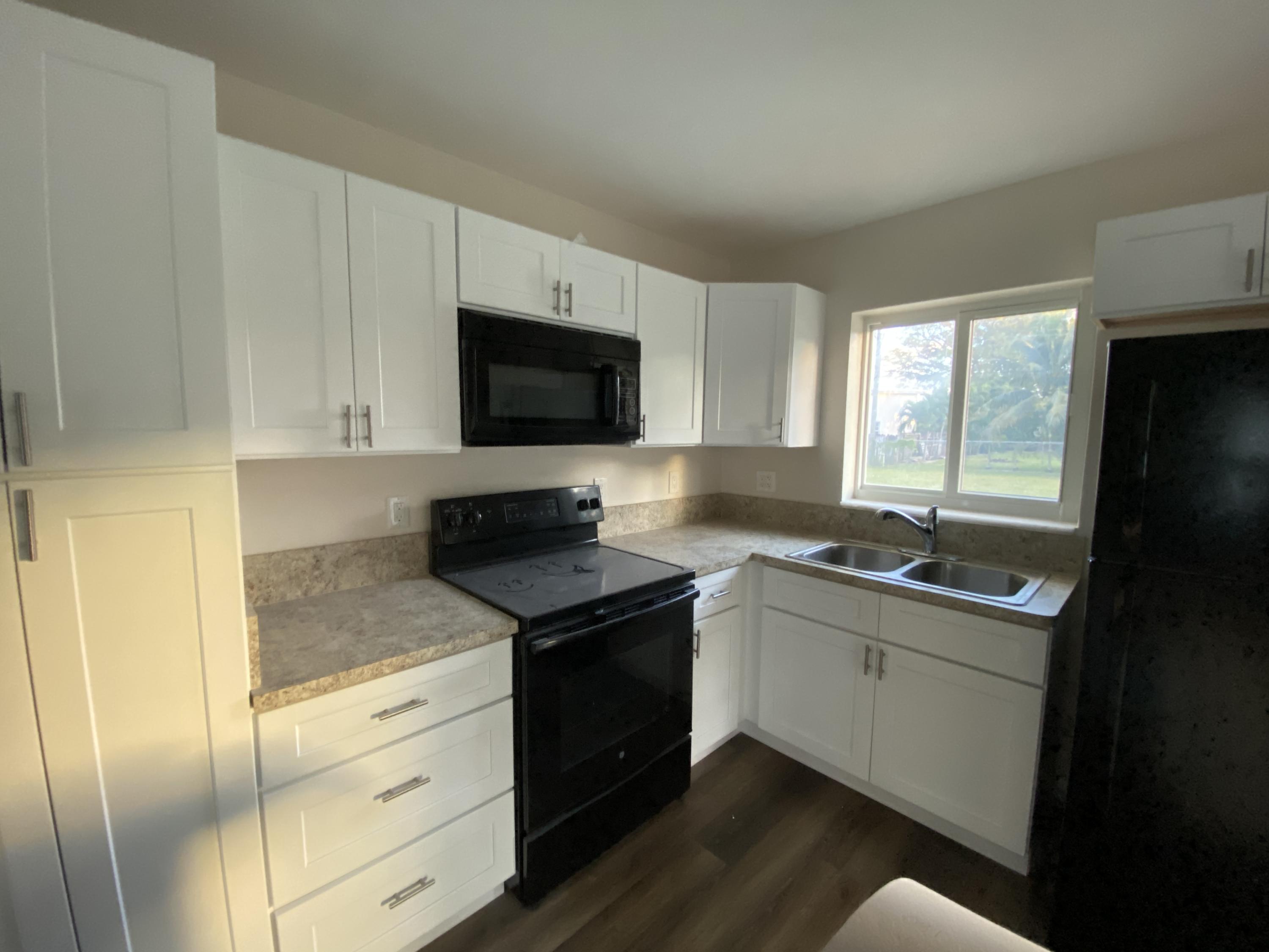 124 Northwest 9th Street Boca Raton, FL 33432 - Photo 10 of 18 a kitchen with granite countertop a sink stainless steel appliances and cabinets