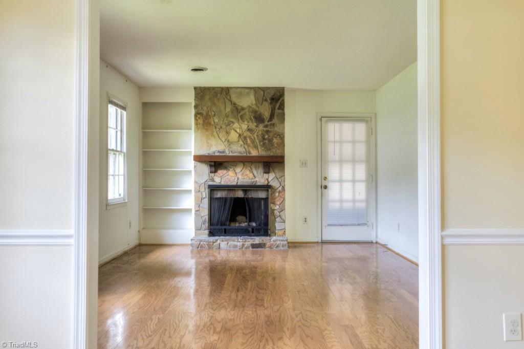 4924 Tower Road, Unit D Greensboro, NC 27410 - Photo 7 of 19 Living room with stone fireplace and built-in shelves, open to the dining room