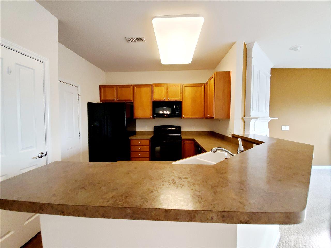 8332 Saltwood Place Raleigh, NC 27617 - Photo 3 of 16 a large kitchen with granite countertop a refrigerator a stove and a sink