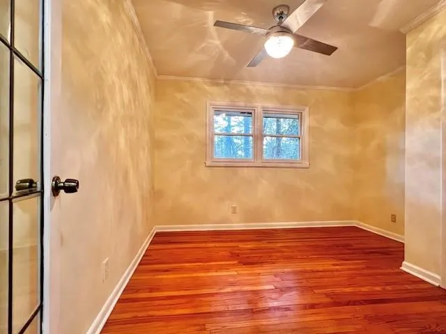 a view of an empty room with wooden floor and a window