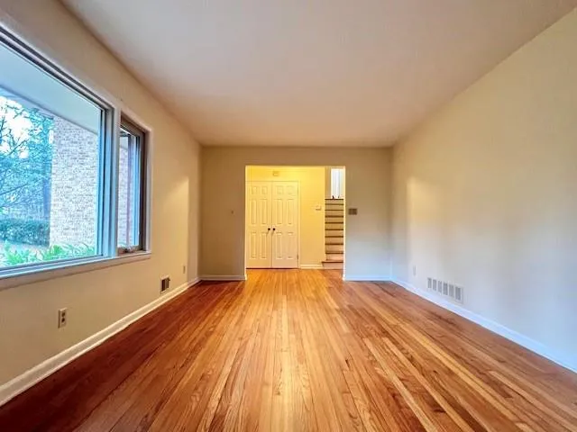 a view of an empty room with wooden floor and a window