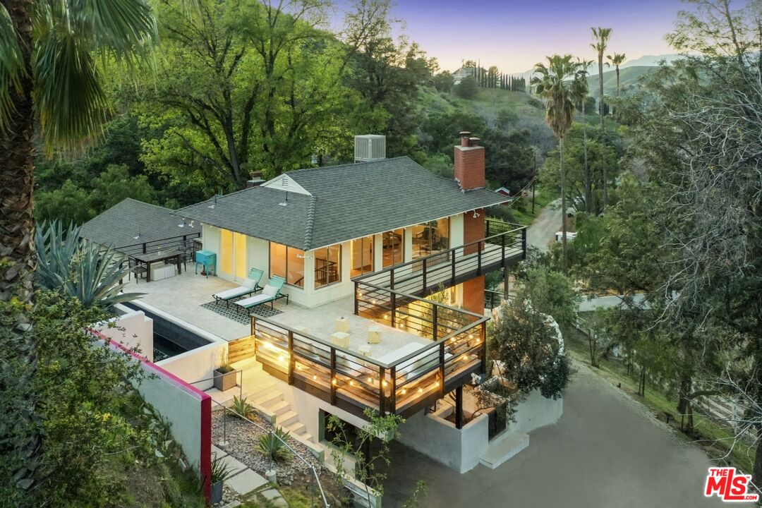 an aerial view of a house with swimming pool and trees