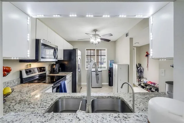 a kitchen with stainless steel appliances granite countertop a sink refrigerator and cabinets