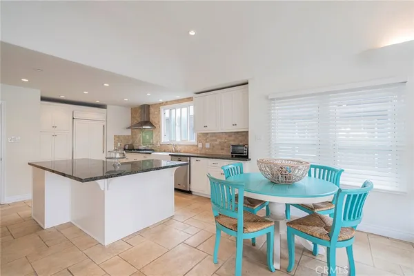 a kitchen with granite countertop white cabinets and chairs