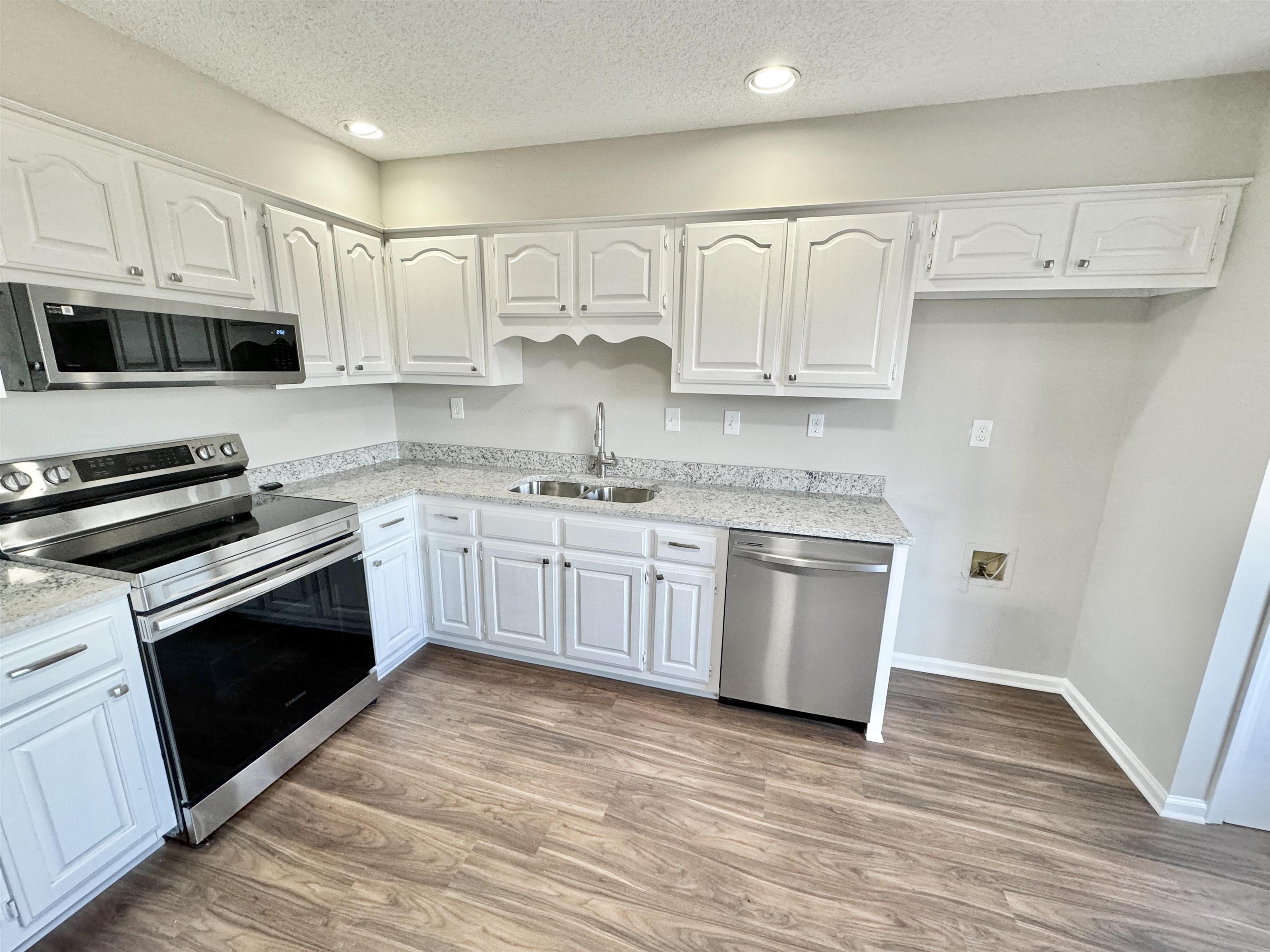 Kitchen featuring sink, light hardwood / wood-style flooring, stainless steel appliances, and white cabinets