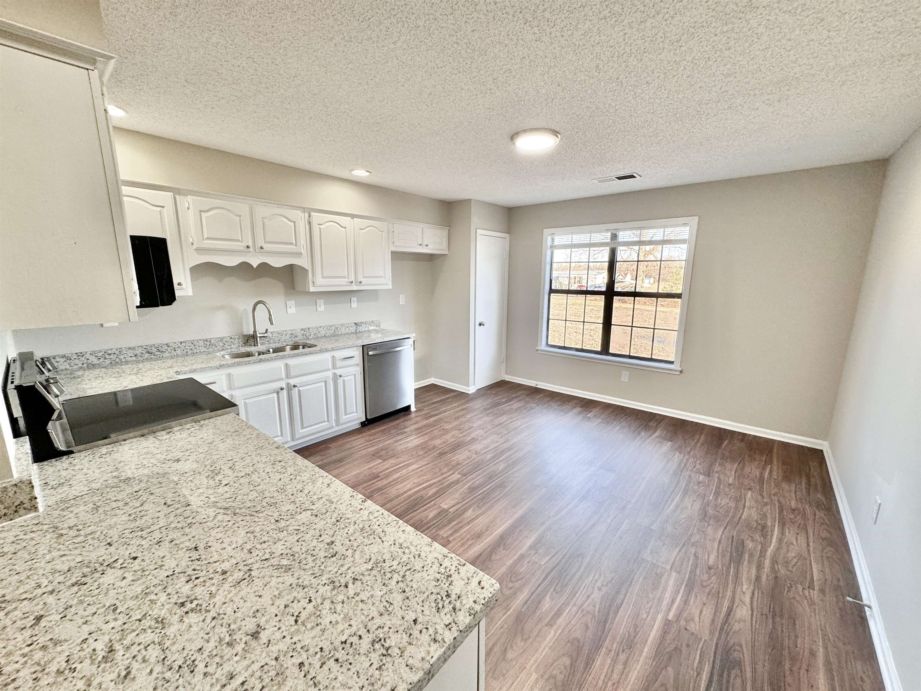 Kitchen featuring dark hardwood / wood-style floors, sink, white cabinets, stainless steel appliances, and a textured ceiling