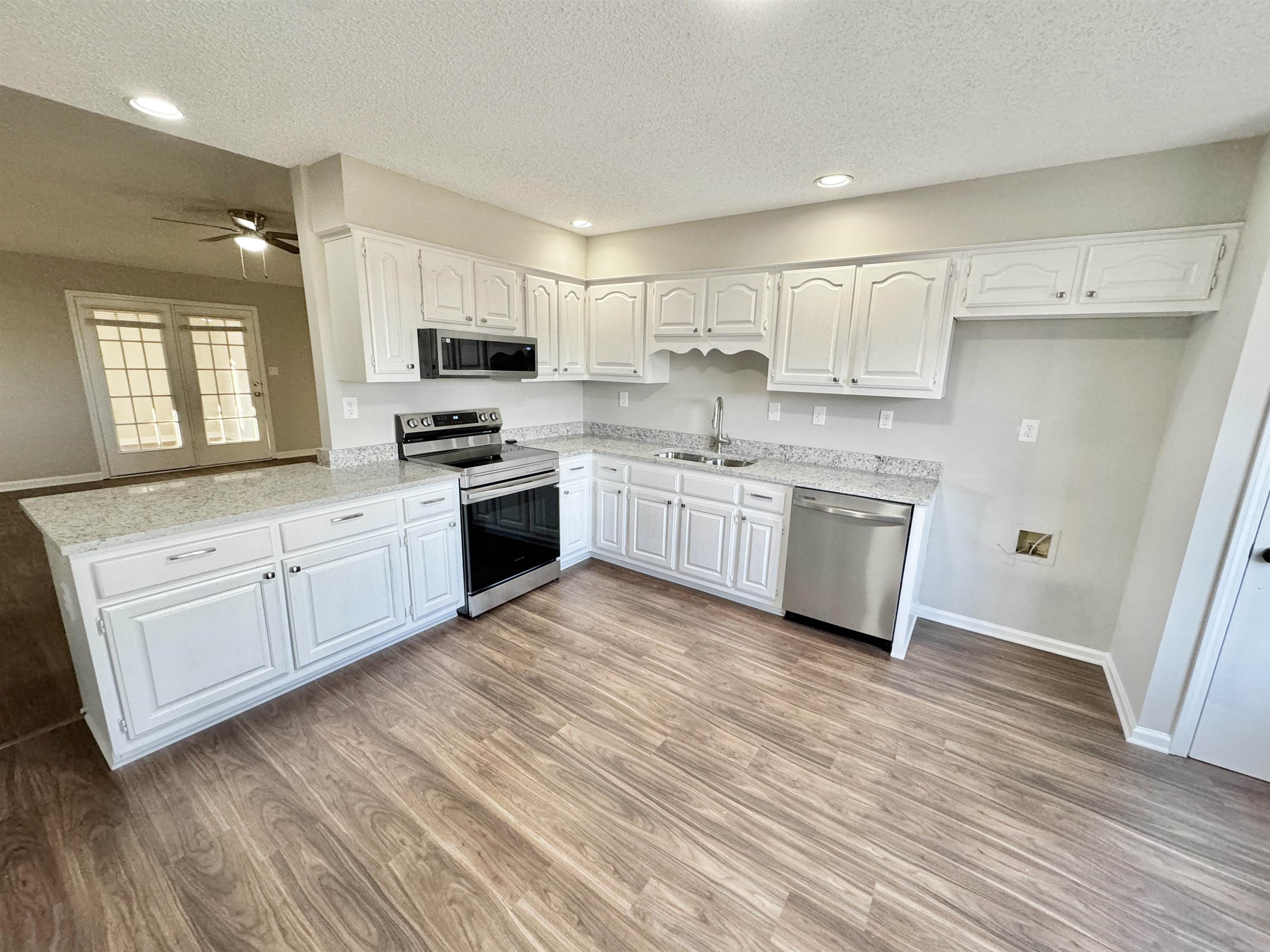 Kitchen featuring stainless steel appliances, white cabinetry, sink, and a textured ceiling