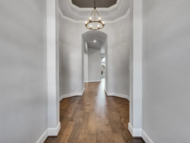 a view of a hallway with wooden floor and a chandelier