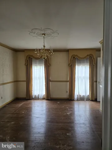 a view of a big room with wooden floor and windows