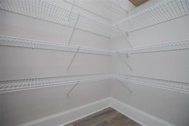 a view of an empty room with closet and a bathroom