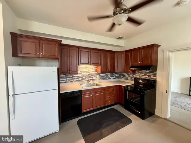a kitchen with granite countertop a refrigerator a stove and a sink