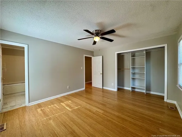 a view of empty room with wooden floor and fan